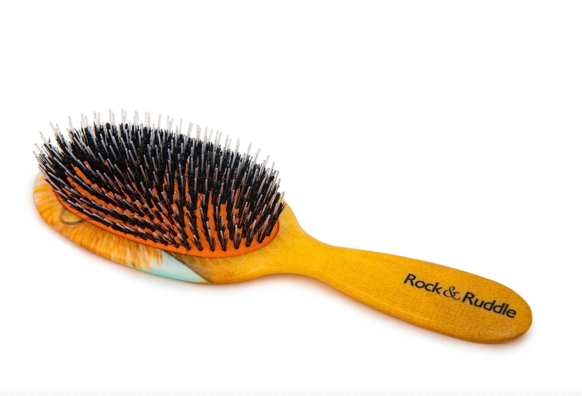 Eclectic Rock & Ruddle baby hairbrush with a golden lion illustration, natural boar bristles, and nylon tips.