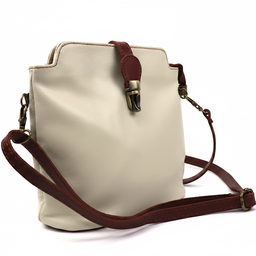 Eclectic Roma leather crossbody bag in cream with tan trim, gold hardware, and adjustable strap on white background.