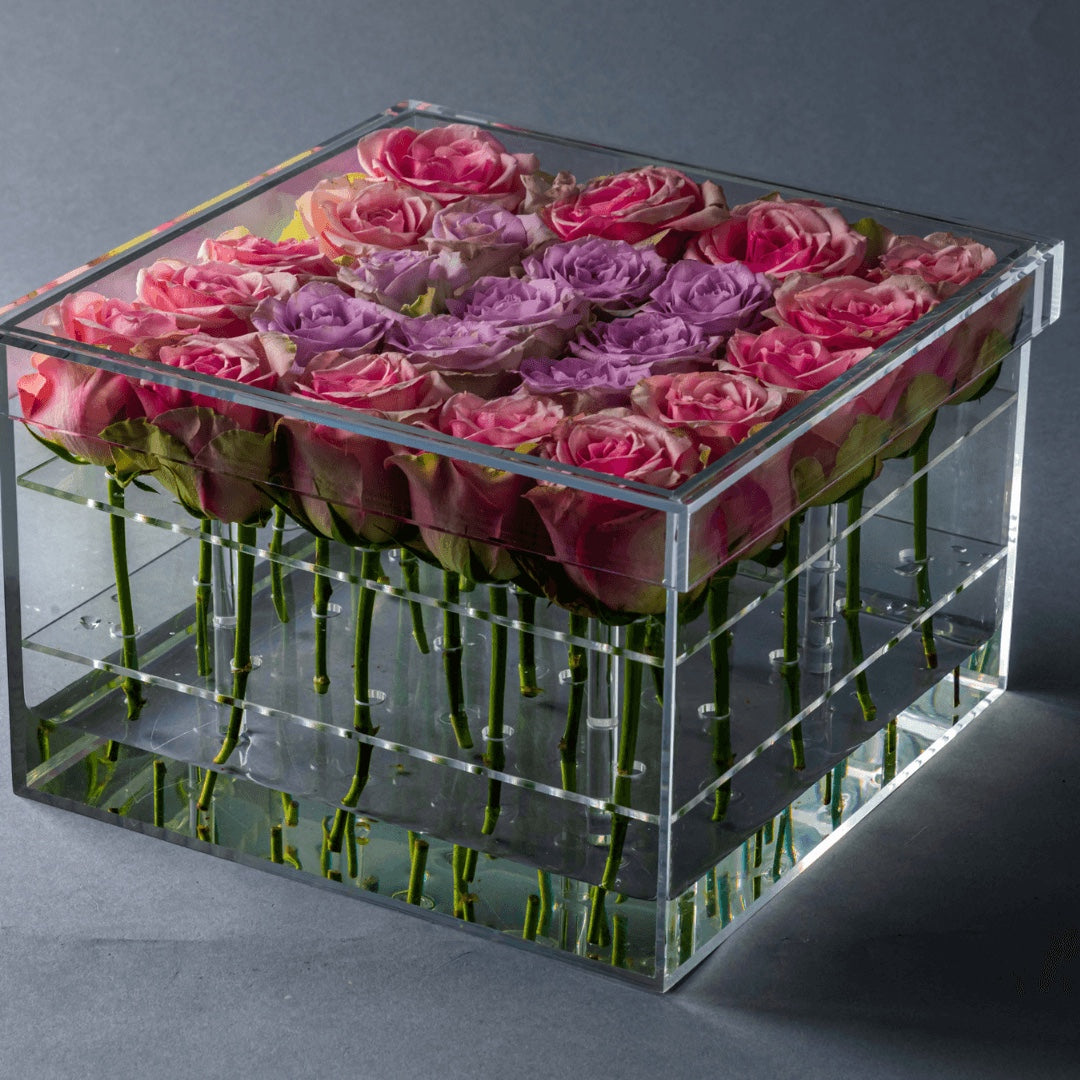 Eclectic rose box featuring a square clear acrylic container filled with vibrant pink and purple roses