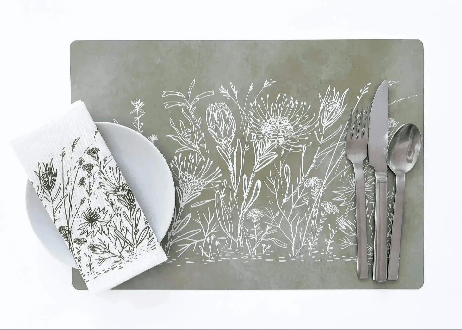 Eclectic sage green reusable placemat with white botanical fynbos illustration, set with cutlery and a matching napkin.
