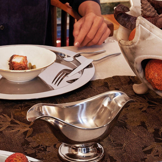 Eclectic Sambonet Elite oval sauce boat in mirror-polished stainless steel on a formal dining table setting.