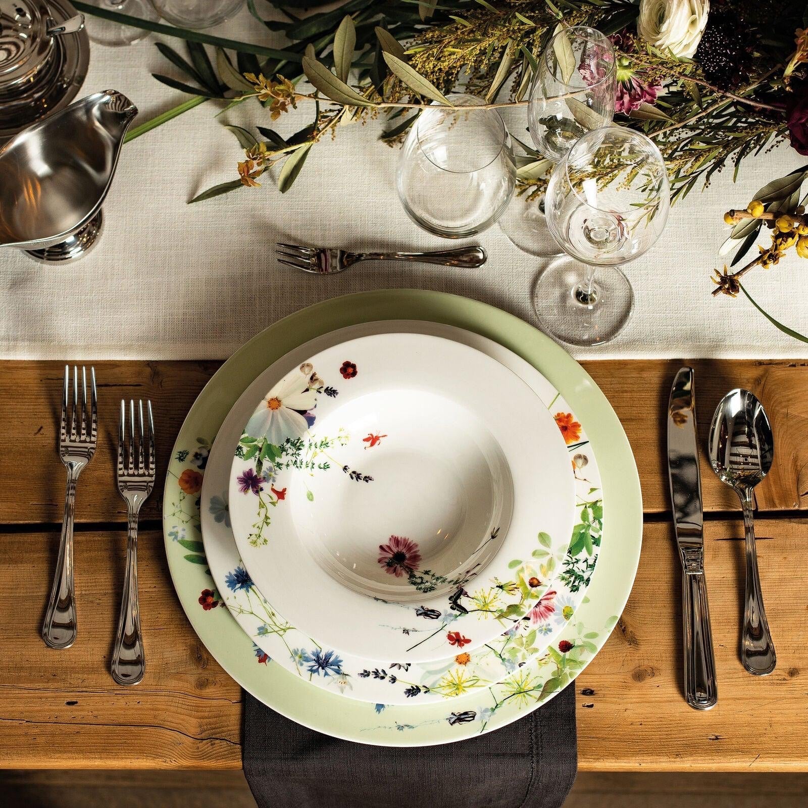 Eclectic Sambonet Elite oval stainless steel sauce boat on a rustic dining table with floral plates and cutlery