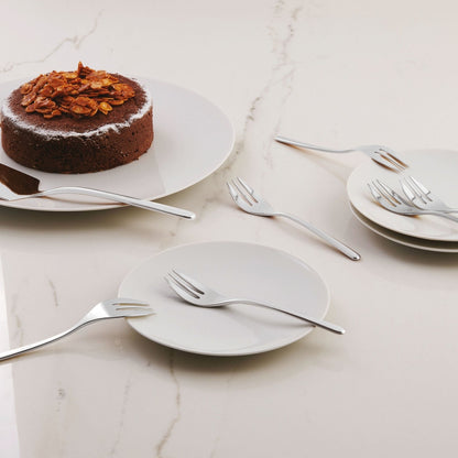 Eclectic Sambonet Linear mirror-polished stainless steel cake server and fork set arranged on a marble table with cake