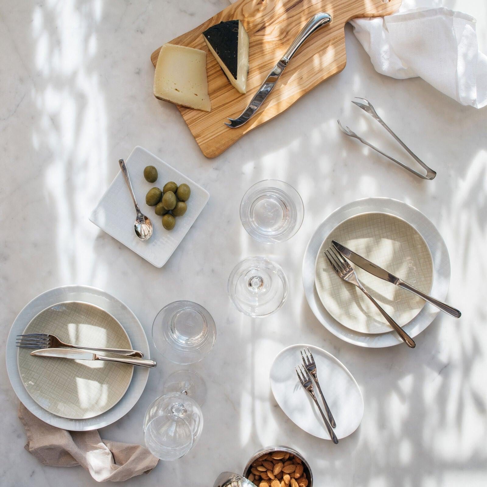 Eclectic Sambonet Living stainless steel ice tongs on a marble table setting with plates and cutlery