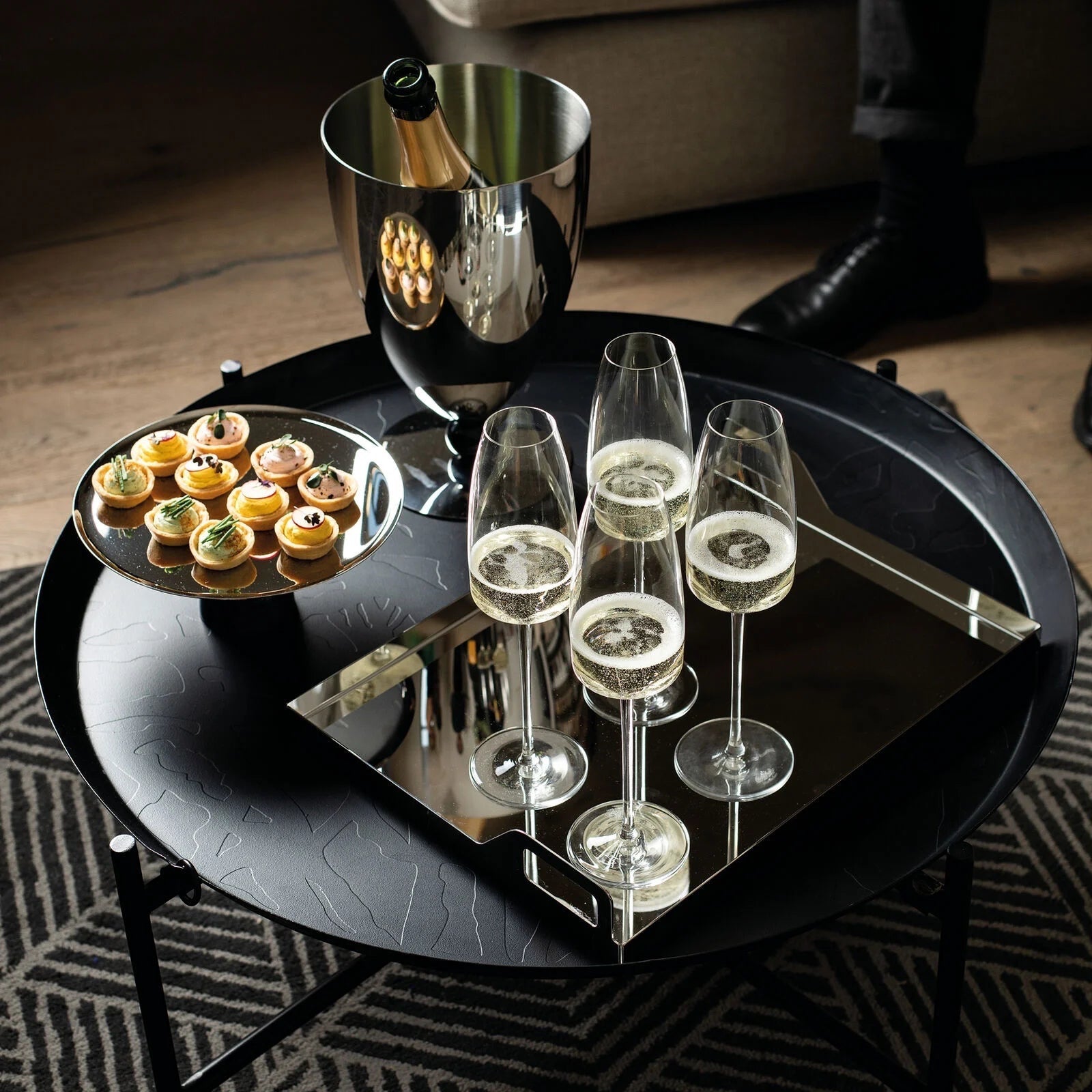 Eclectic Sambonet Penelope ice bucket in mirror-polished stainless steel with black marble-effect base on a table.
