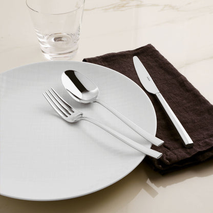 Eclectic Sambonet Rock mirror-polished stainless steel cutlery set with fork, spoon, and knife on a white plate.