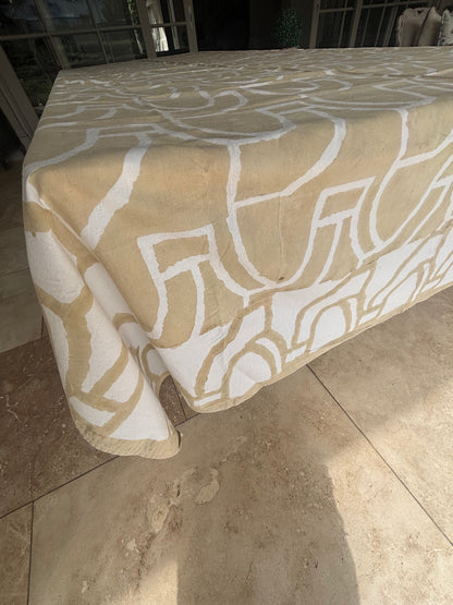 Eclectic 100% cotton tablecloth in sand and white with a bold abstract pattern draped over a large dining table