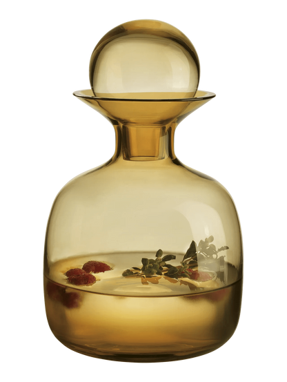 Eclectic Sarabi amber mouth-blown glass carafe with a spherical stopper, filled with infused water and berries.
