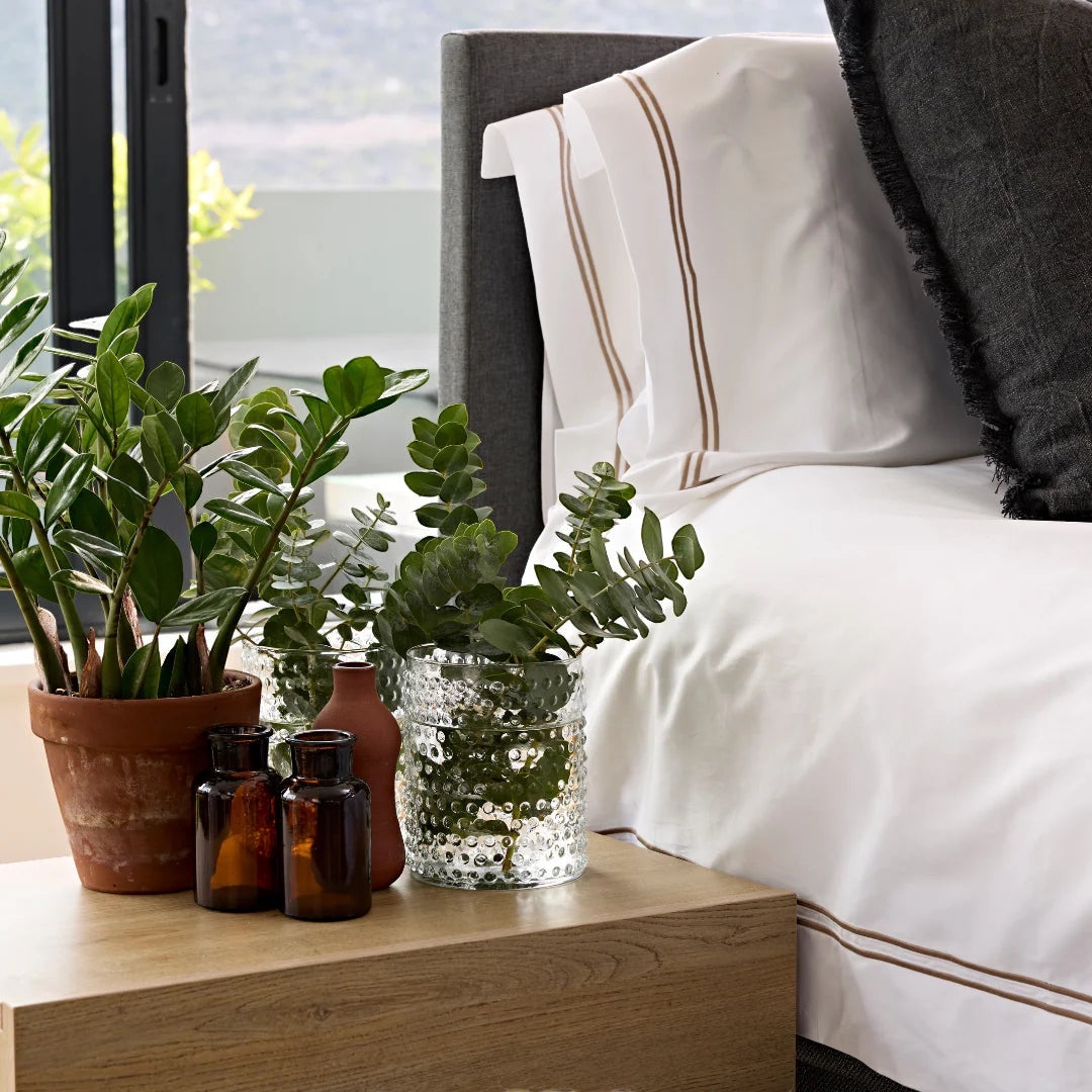 Eclectic Saxon cotton sateen duvet set in white with stone satin stitch detail on a bed with plants on a side table
