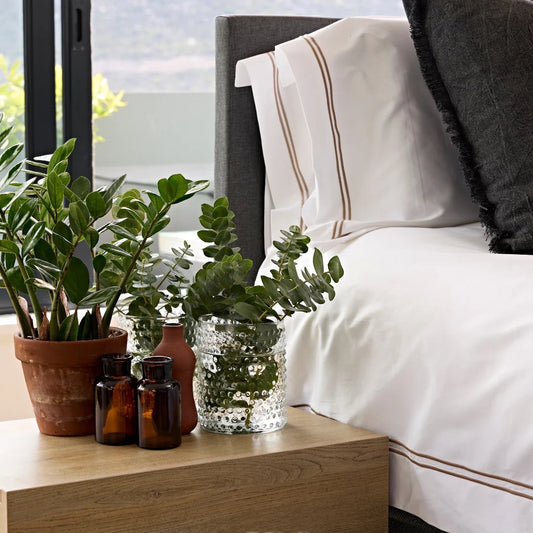 Eclectic Saxon cotton sateen duvet set in white with stone satin stitch detail on a bed with plants on a side table