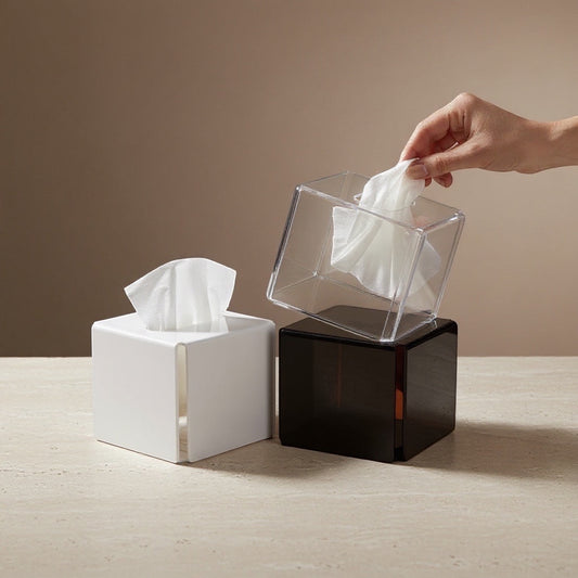 Eclectic modern square acrylic tissue boxes in white, black, and clear, with a hand pulling a tissue from the clear box.