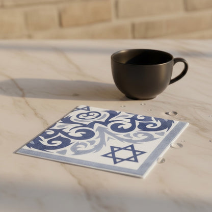 Eclectic blue and white disposable napkin with Star of David and ornamental pattern on a marble table with a cup.