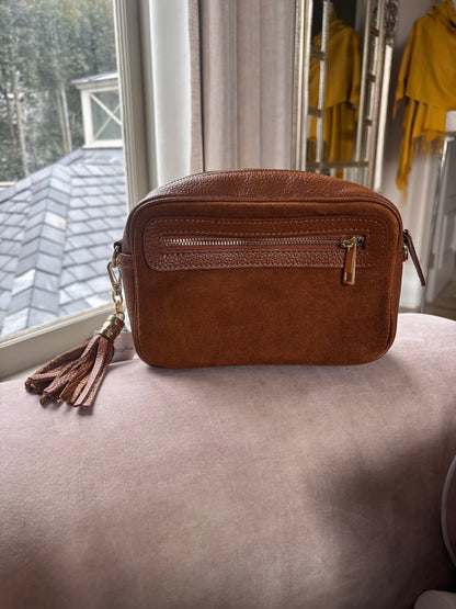 Eclectic tan suede and leather crossover bag with a decorative tassel and front zip compartment.