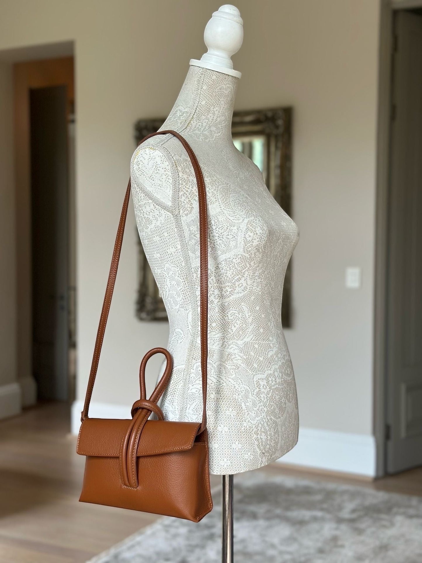 Eclectic Venezia taupe pebbled leather wrist bag with a detachable strap worn crossbody on a mannequin