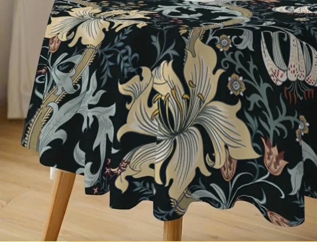 Eclectic round tablecloth featuring a vintage floral pattern in cream, green, and gold on a black drip-dry fabric.