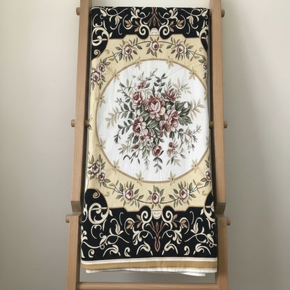 Eclectic vintage round tablecloth featuring a baroque floral pattern in black, gold, and ivory on lightweight fabric.