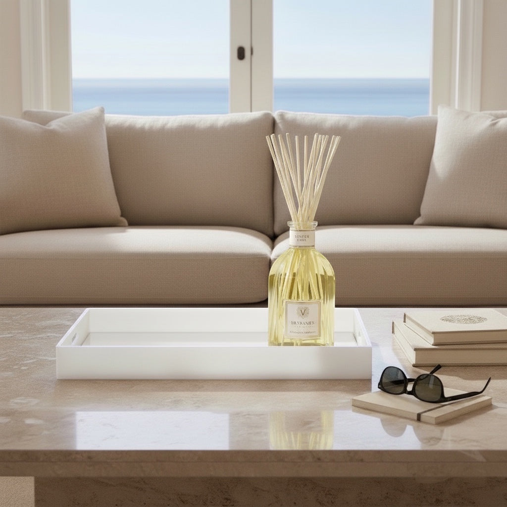Eclectic white acrylic serving tray with a mirrored base styled on a coffee table with a diffuser and books.