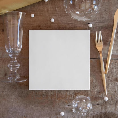 Eclectic white linen-feel airlaid napkin on a rustic wooden table with gold cutlery and glassware