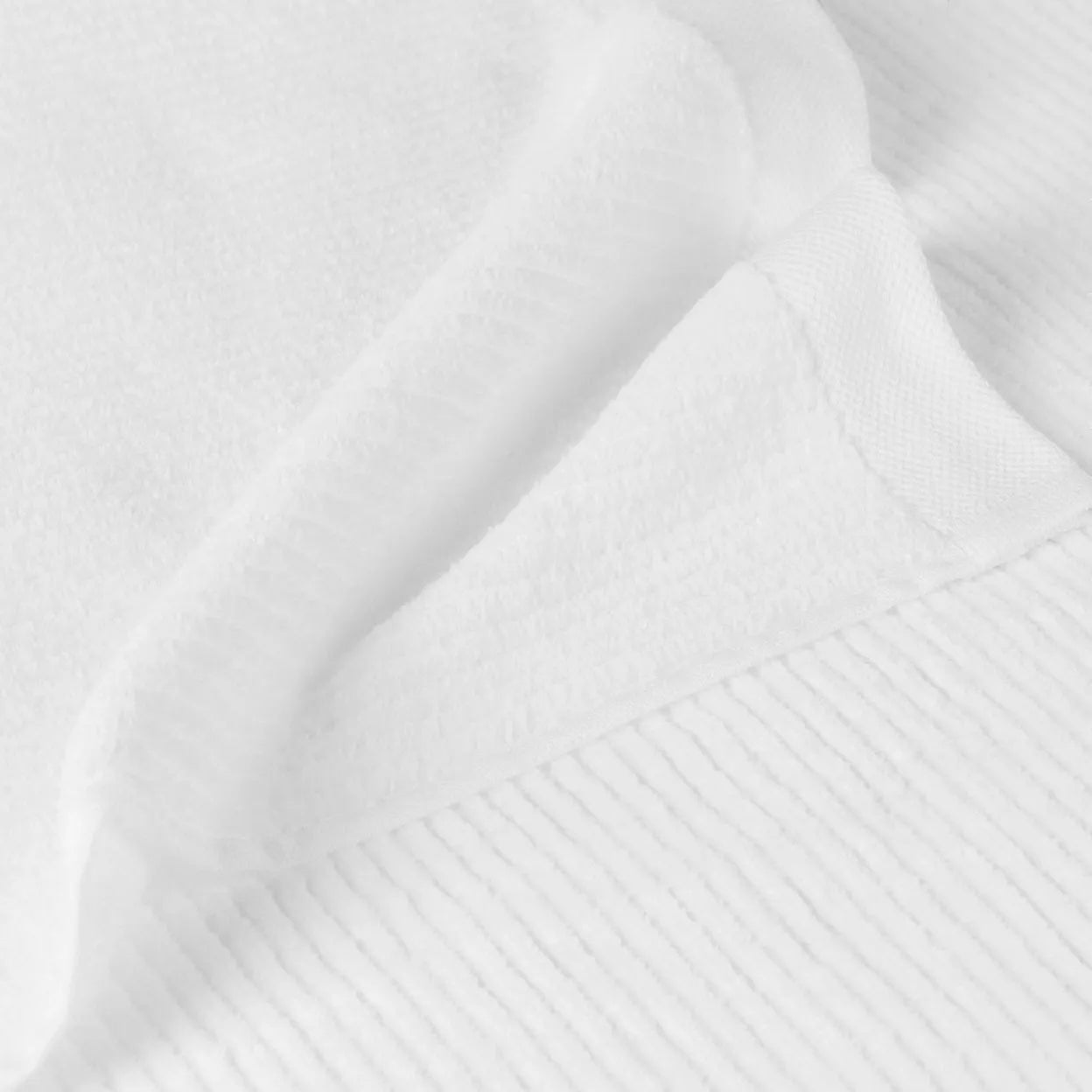 Eclectic white cotton guest towel with a soft velvety finish and ribbed texture detail.
