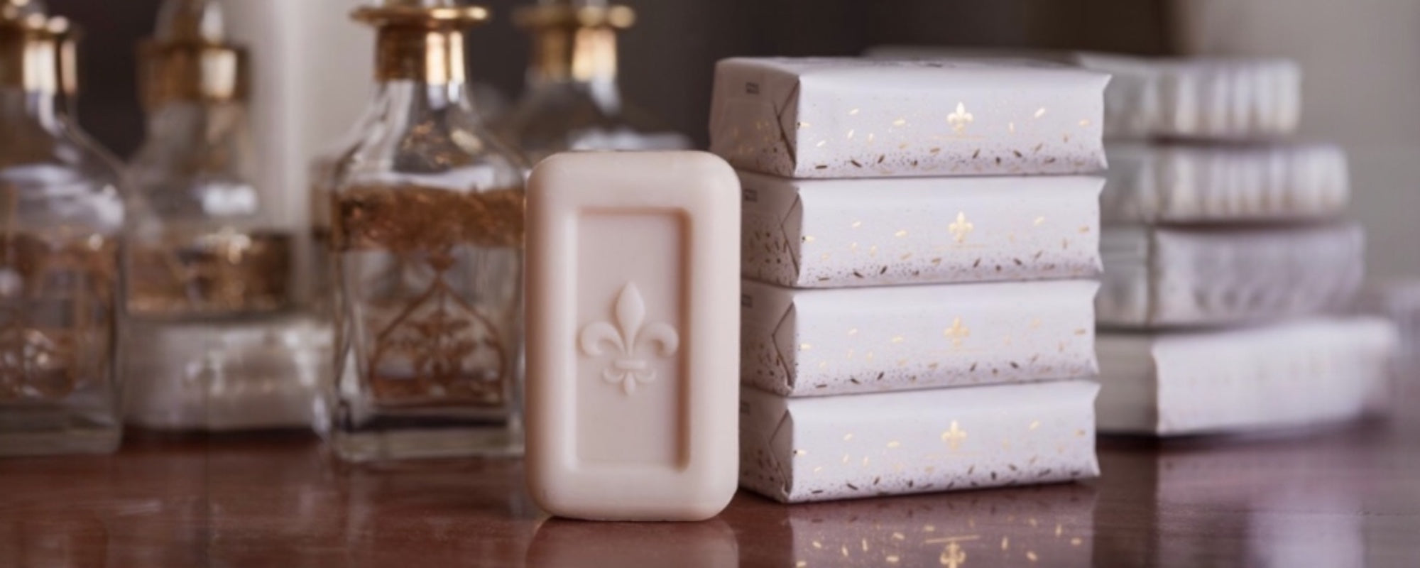 Hand and body scents collection with soaps, lotions, and glass bottles displayed on a wooden surface.