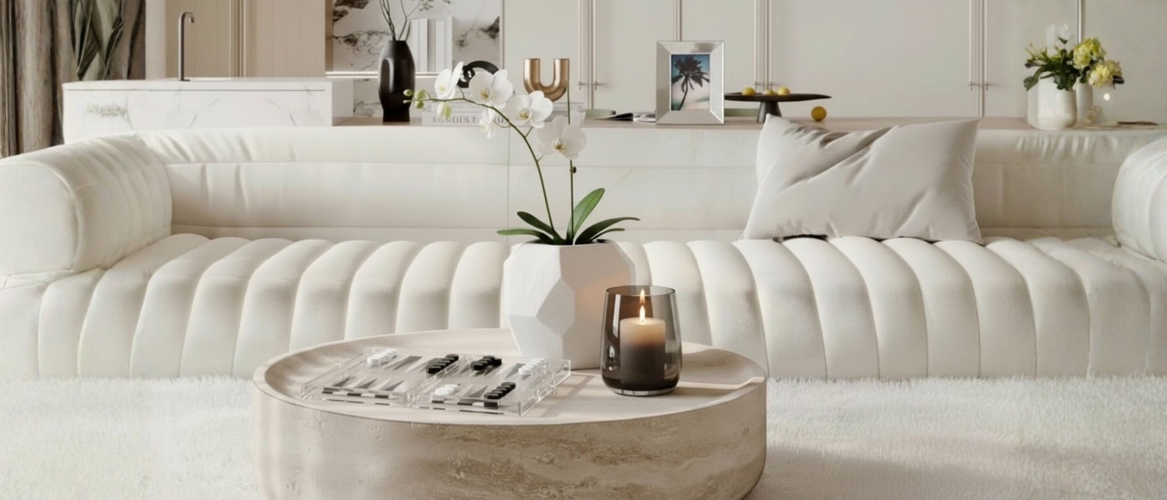 Elegant living room with decorative objects, sculptures, orchid flowers, candle, and coffee table décor.