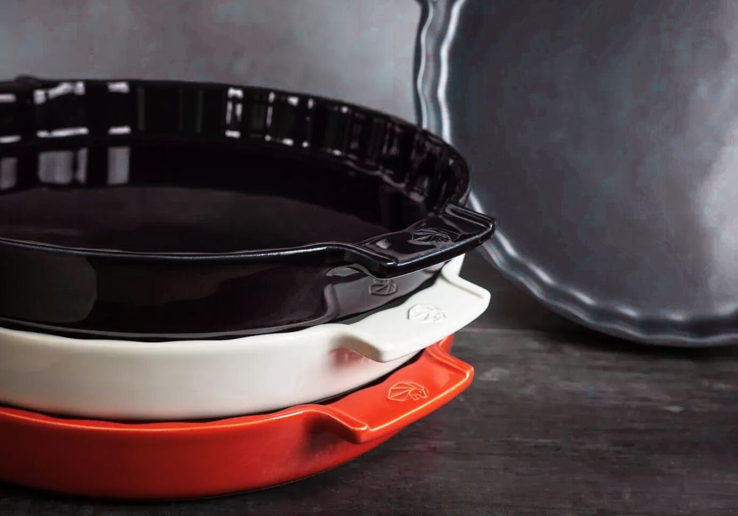 Pie and tart dishes stacked in black, white, and red ceramic finishes.