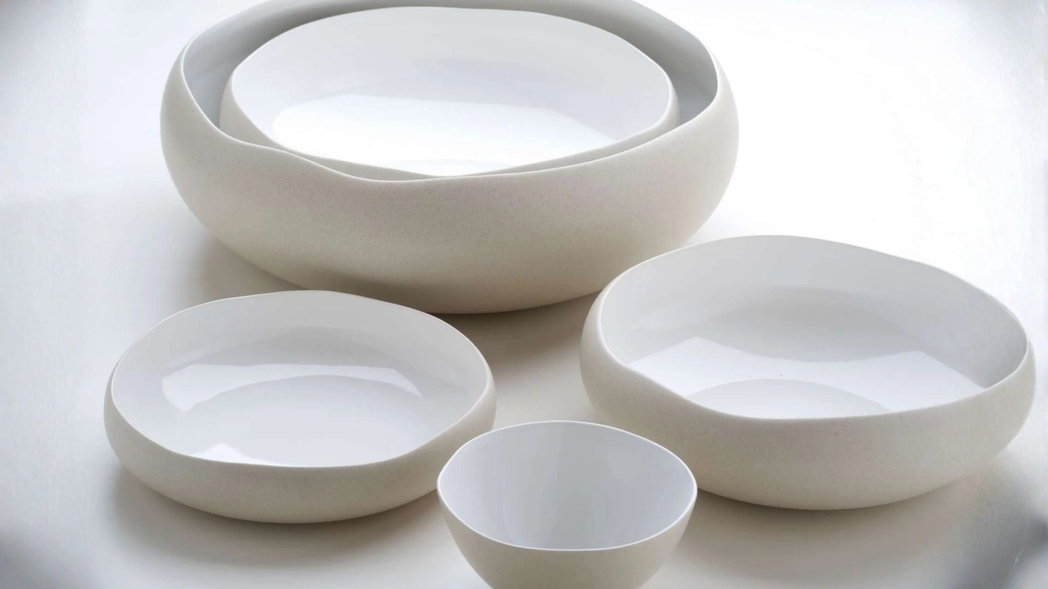 White ceramic serving bowls in different sizes arranged on a light tabletop.