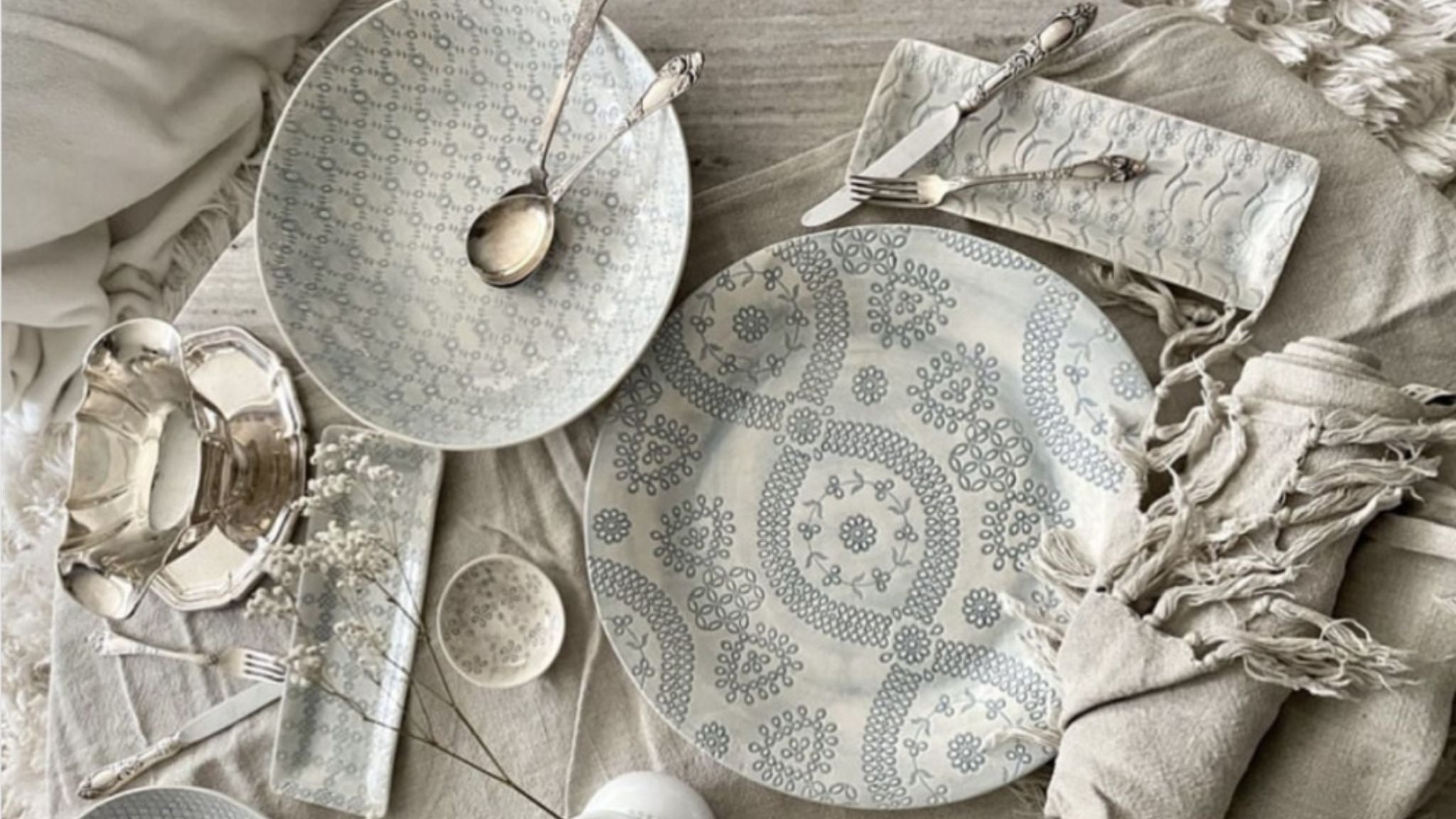Decorative serving platters and dishes styled with linen and tableware.